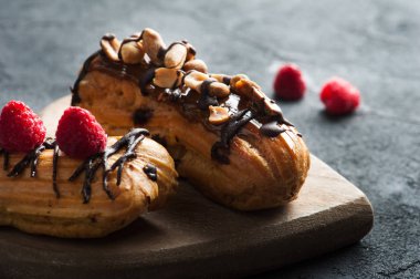 Eklerleri fıstık, çikolata sosu ve ahududu