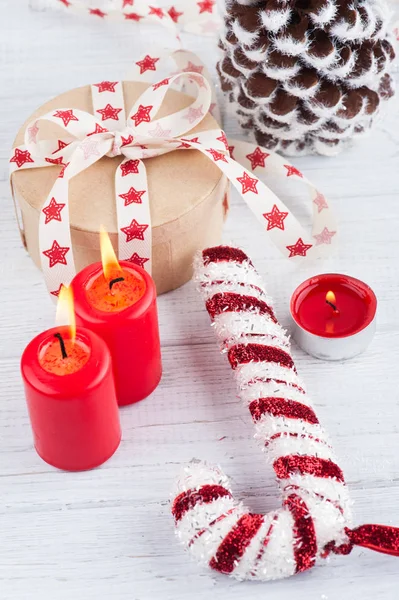 Geschenk in Kraftbox mit rotem Sternenband, brennenden Kerzen und Deko — Stockfoto