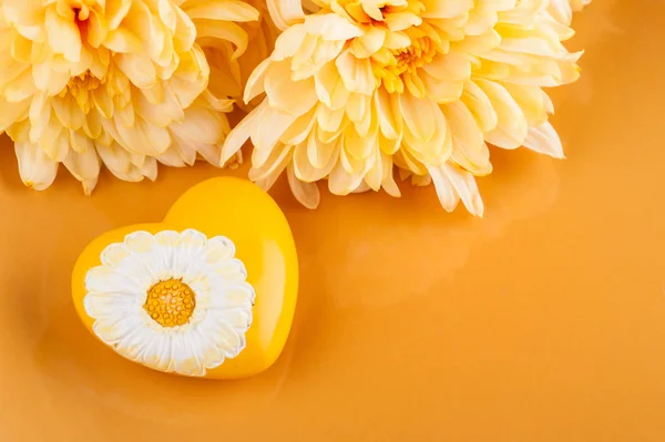 Chrysanthemum flowers on a plate and heart — Stock Photo, Image