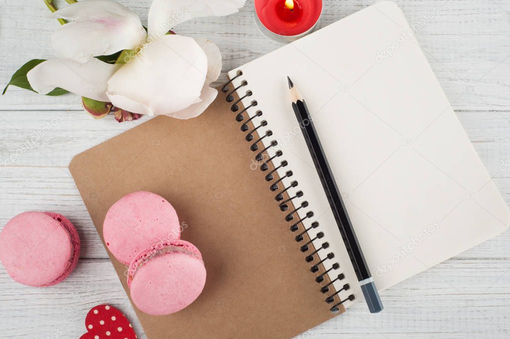 Blank notebook, pink macaroons, lit candle