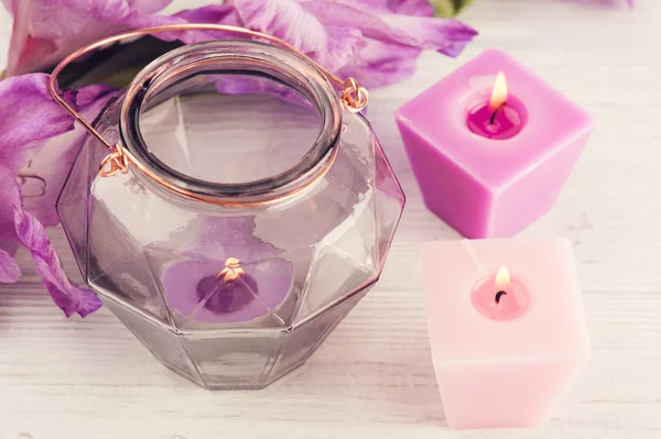 Фіолетовий гладіолус і запалені свічки на білому столі — стокове фото