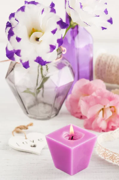 紫のトルコギキョウの花と白いテーブルにキャンドルを点灯しています。 — ストック写真
