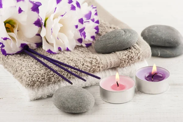 Wellness-Komposition mit Handtüchern, brennenden Kerzen, lila Aromastäbchen — Stockfoto