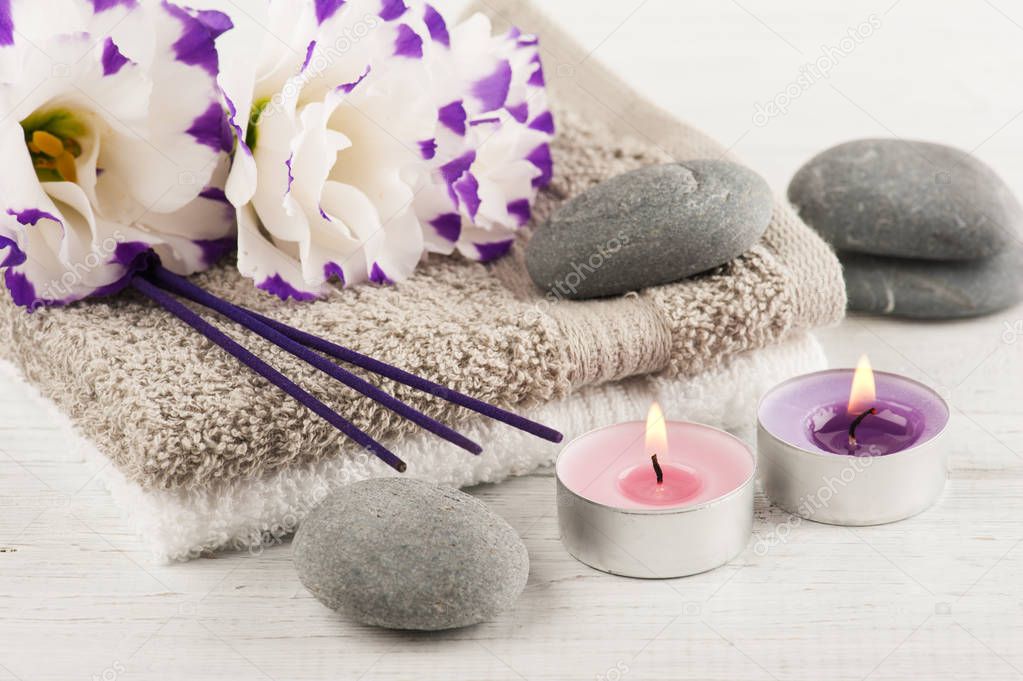 Spa composition with towels, lit candles, purple aroma sticks