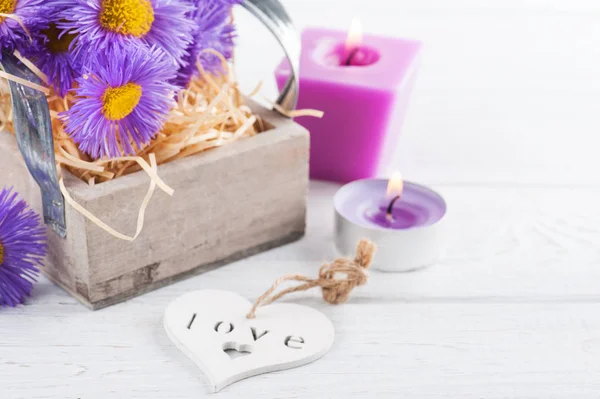 紫雏菊和白色桌上点燃蜡烛 — 图库照片