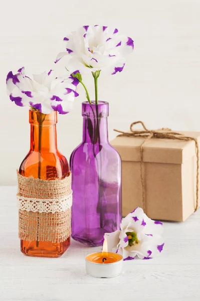 Фиолетовые цветы и зажжённые свечи на белом столе — стоковое фото