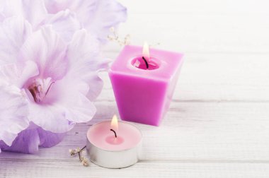 Çiçekler ve beyaz masa üzerinde yanan mum