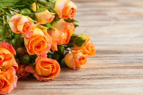 Świeże róże pomarańczowe kwiaty na podłoże drewniane — Zdjęcie stockowe