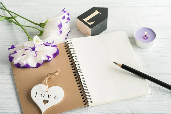 Caderno em branco, vela, flores de eustoma — Fotografia de Stock