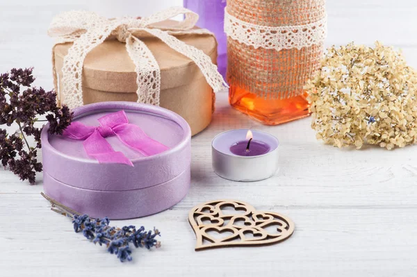 Фиолетовые цветы и зажженная свеча на белом столе — стоковое фото