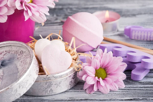 SPA composition with pink bath bombs, daisy flowers, lit candle — Stock Photo, Image