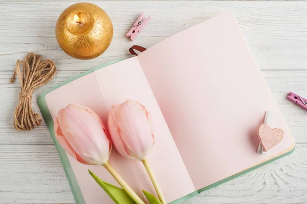 Różowy notebook, tulipany i świeci świeca — Zdjęcie stockowe