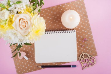 Defter, çiçek ve yanan mum