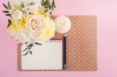 Defter, çiçek ve yanan mum