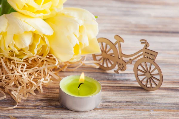 Желтые тюльпаны, зажженная свеча — стоковое фото