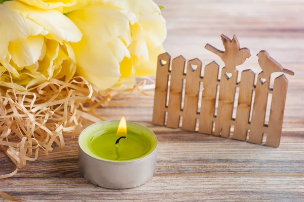 Желтые тюльпаны, зажженная свеча — стоковое фото