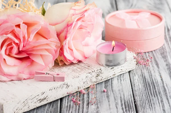 Розовая подарочная коробка, розы, зажженная свеча — стоковое фото