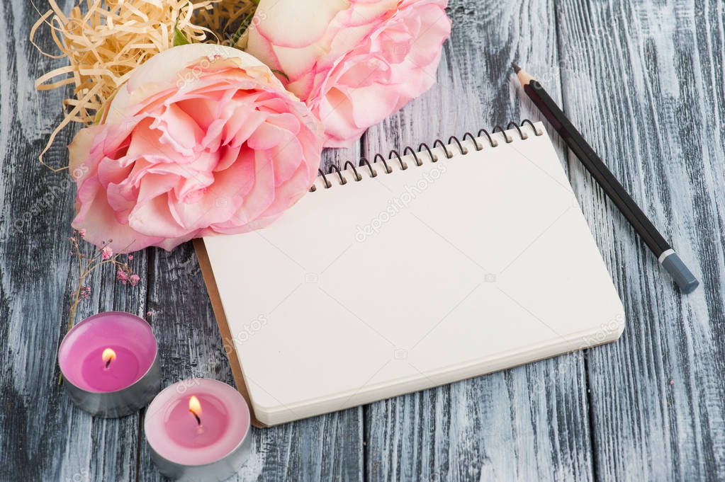 Notebook, flowers and lit candles