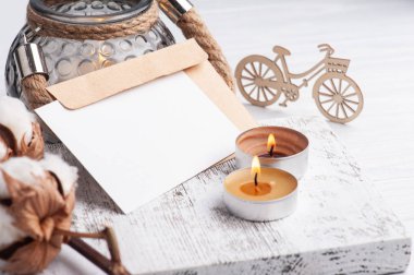 Kalitesiz ahşap arka planda boş not ve kraft zarfı. Metin ve yanan mumlar için alanı kopyala