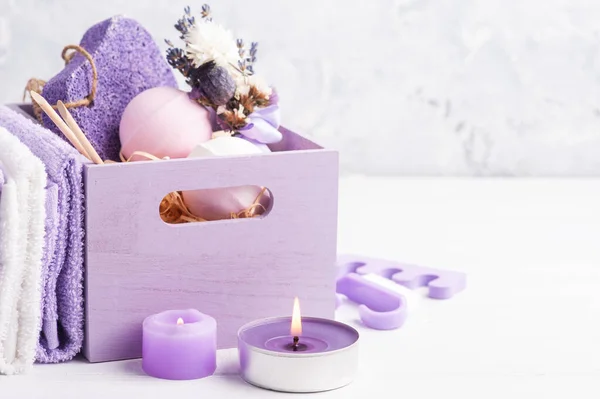 香喷喷的洗浴炸弹 紫色的松果和薰衣草在水疗中心的木箱里 前面点亮紫色的蜡烛 — 图库照片