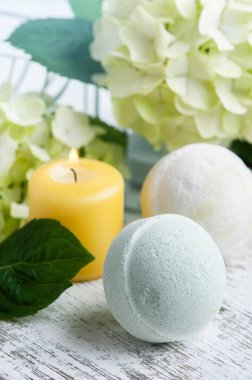 Spa 'da yeşil aroma bombaları beyaz ahşap arka planda hortensiya çiçekleri ve yapraklarla hayat buluyor.