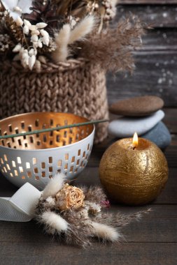 Şık ahşap arka planda Aroma altın mumu. Arka planda kurumuş çiçekler ve çakıl taşları