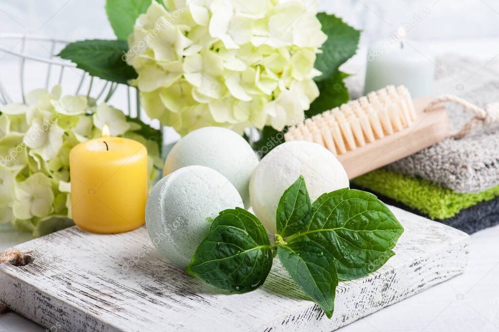 Green aroma bath bombs in Spa still life on white wooden background with hortensia flowers and leaves