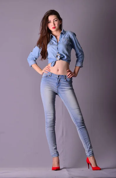 Jeune femme asiatique sexy avec des cheveux longs et jambes modèle de style denim posant sur un fond gris — Photo