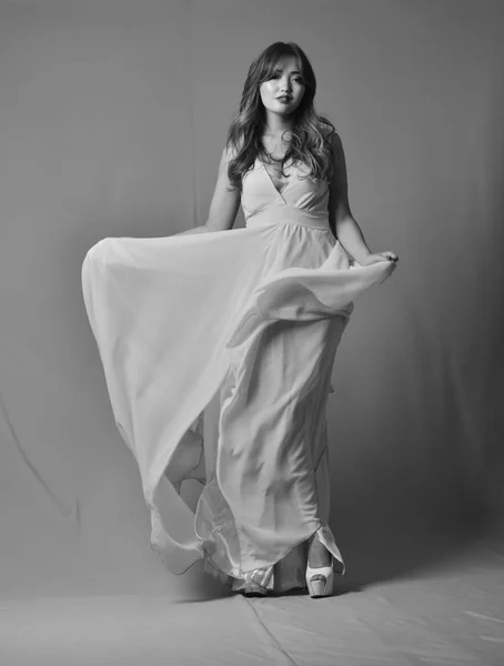 Young asian model posing in elegant long dress fluttering in the wind — Stock Photo, Image