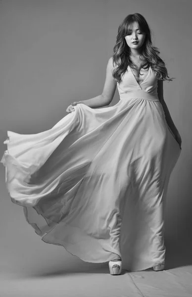 Young model posing in elegant long dress fluttering in the wind — Stock Photo, Image