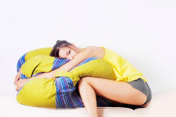 Asian woman in a yellow T-shirt and wrestling shorts on a yellow cushion — Stock Photo, Image