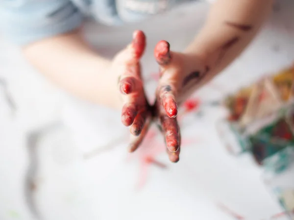 Küçük bir çocuk küçük bir çocuğun ellerini boyuyor..