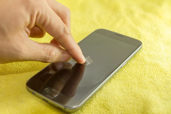 Limpieza de la pantalla del teléfono móvil mediante cinta adhesiva transparente — Foto de Stock