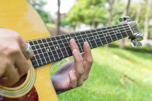 Playing harmonic sound guitar in the park — Stock Photo, Image