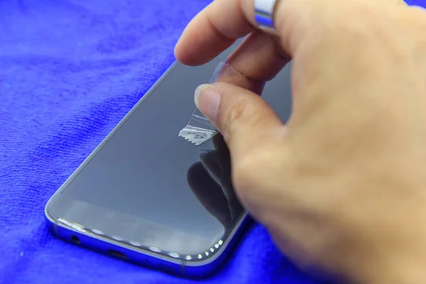 cleaning mobile phone screen by adhesive clear tape.