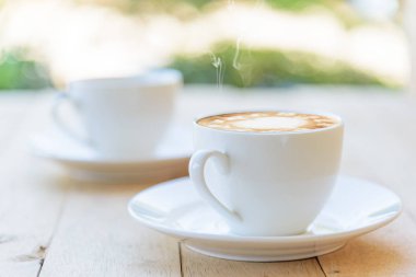 Sıcak kahve, sıcak kapuçino ve güzel desenli süt köpüğü. 