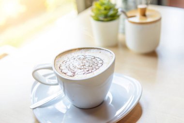 Sıcak kapuçino. Masanın üzerinde köpük desenli güzel bir kahve.