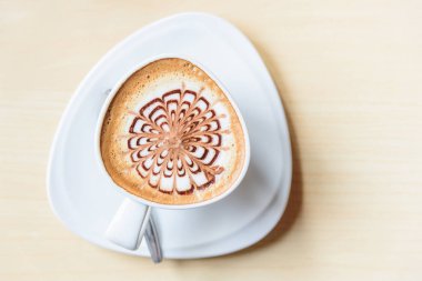 Sıcak kapuçino. Masanın üzerinde köpük desenli güzel bir kahve.