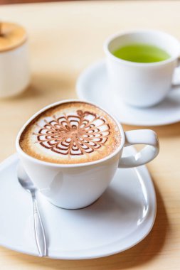 Sıcak kapuçino. Masanın üzerinde köpük desenli güzel bir kahve.