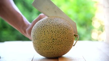 Bıçak kullanan adam portakallı karpuzu ahşap tabakta ikiye böldü.