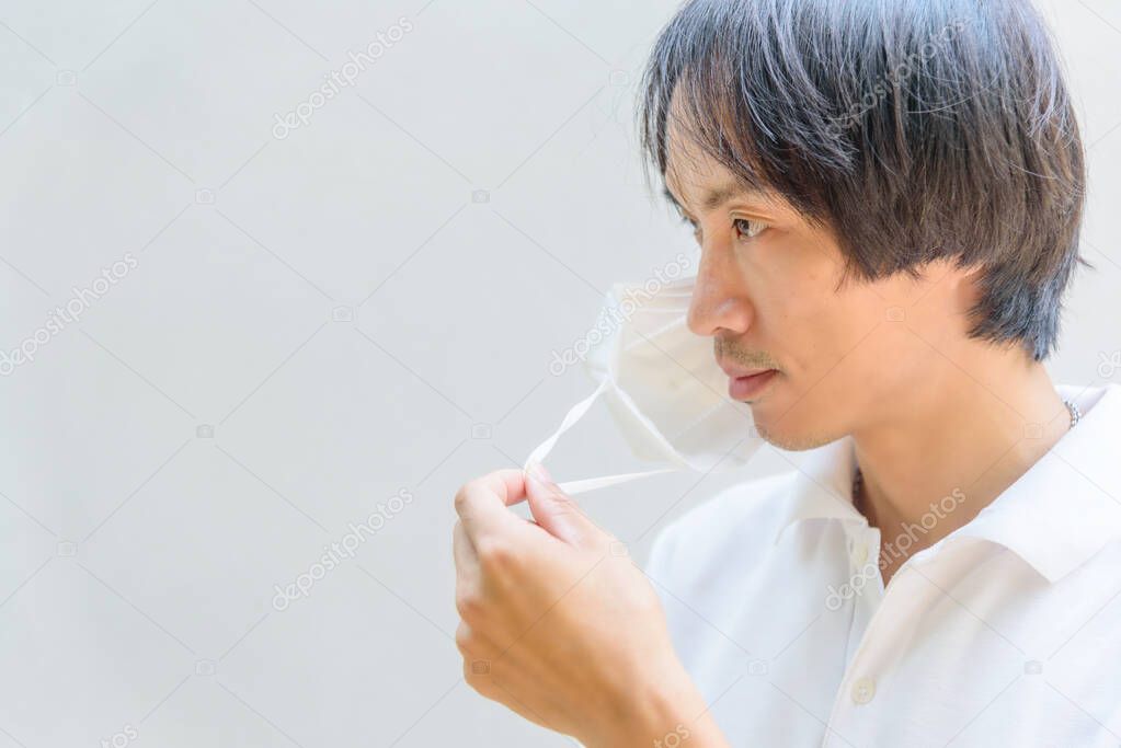 A asian man remove the N95 mask from his face 