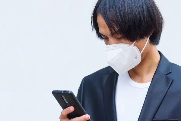 Ένας Ασιάτης Φοράει Μάσκα N95 Και Χρησιμοποιεί Smartphone — Φωτογραφία Αρχείου