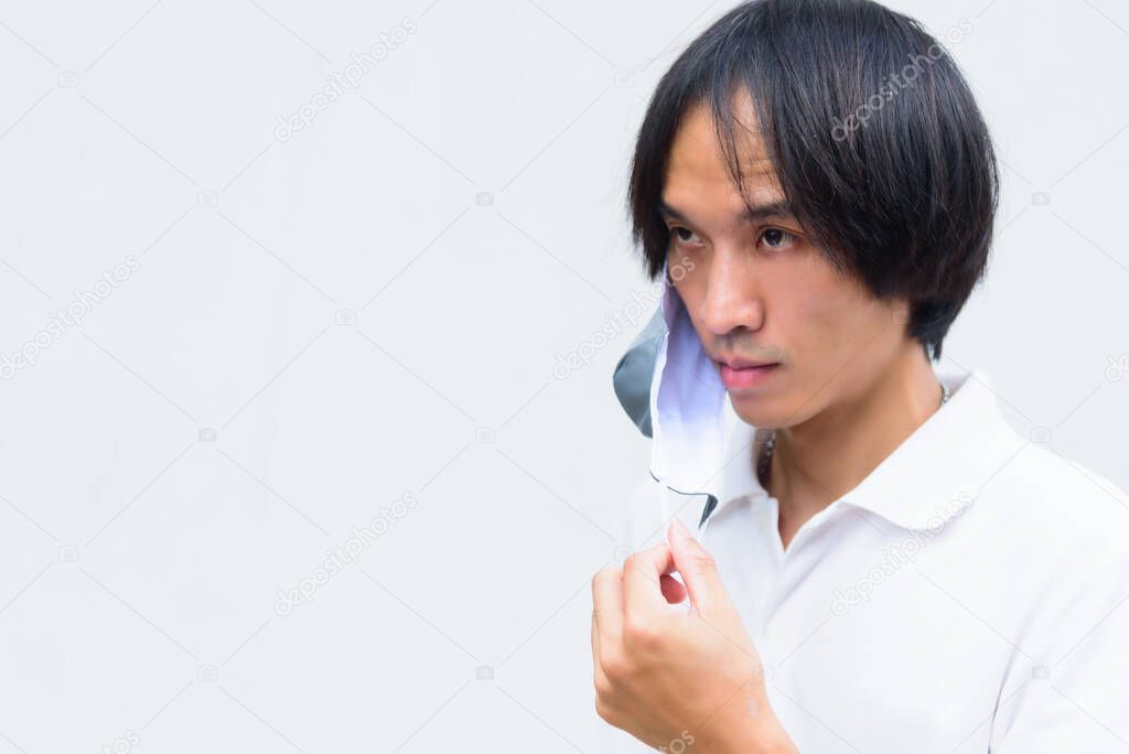 A asian man remove the cloth mask from his face 