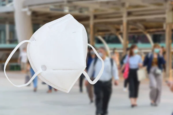 Beyaz N95 Maskeli ve mavi insanlar arka planda