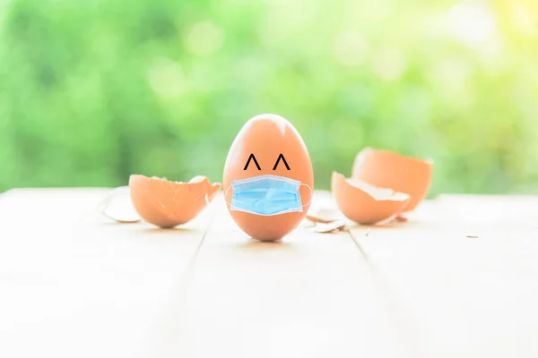 Egg wear the hygienic mask and Broken Egg shell background / safe egg from covid-19 with hygienic mask idea