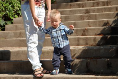 Mom teaches baby to go down the stairs clipart
