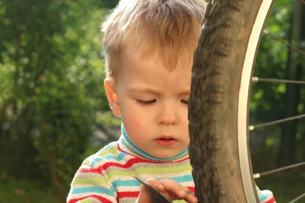 A boy plays with a Bicycle wheel upside down — Stock Photo, Image