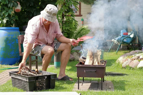 Nonno accende il fuoco in giardino per cucinare — Foto Stock