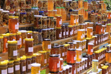 Çeşitli bal kavanozları olan raflar. Bal, bal arıları ve bazı ilgili böcekler tarafından yapılan tatlı, yapışkan bir besin maddesidir..