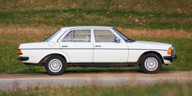 CLUJ-NAPOCA, ROMANIA - 5 Ağustos 2011: Klasik Mercedes-Benz W 123 beyaz sedan araba gün batımında doğada